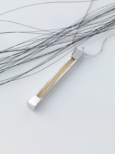 Forged Farriers Nail sterling silver pendant with cream square-braided horse hair, shown on a silver chain beside loose black horse tail hairs.