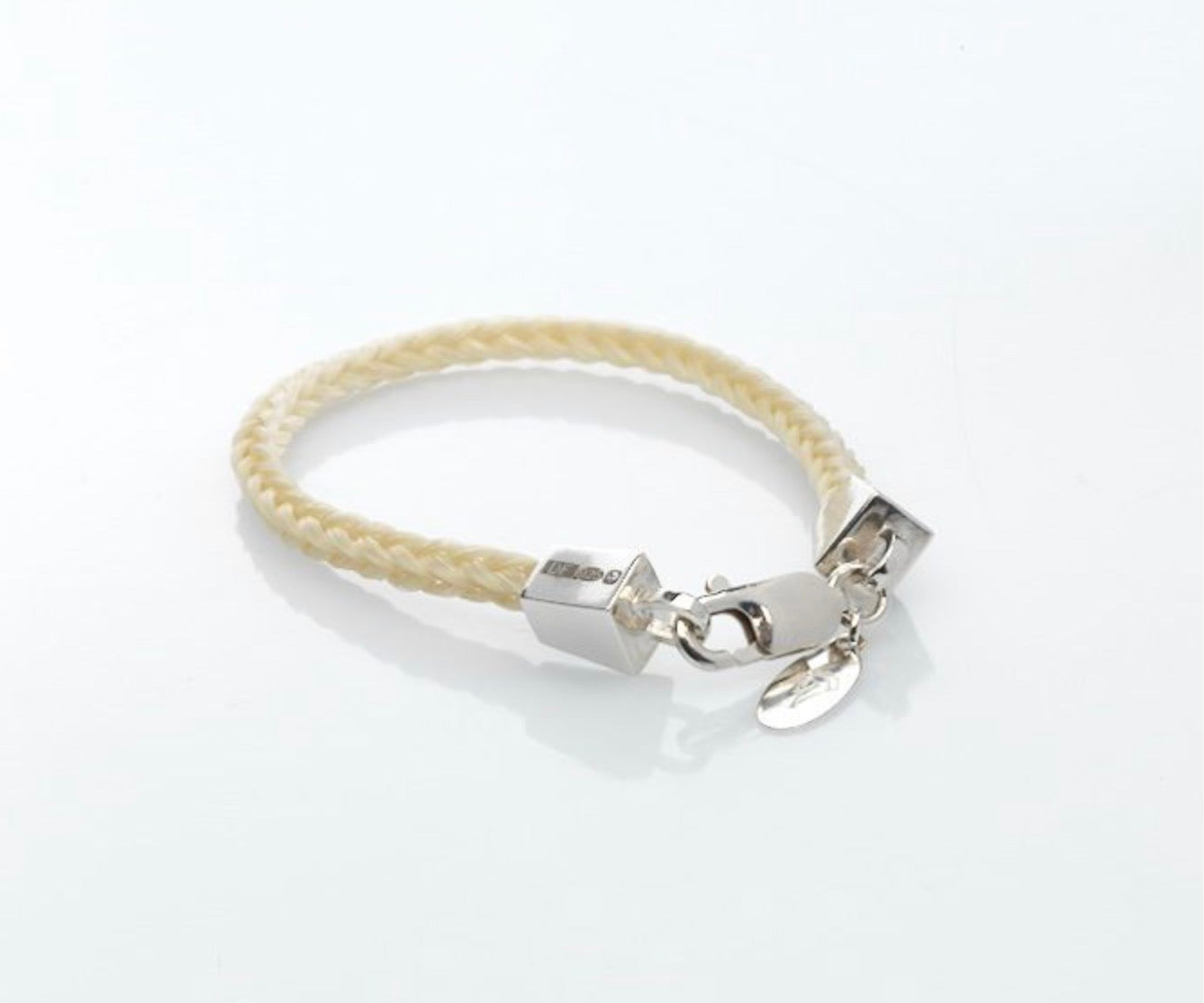 Full view of a white or grey handbraided horse hair bracelet from the Forged Farriers Nail range, with sterling silver lobster clasp and engraved tag.